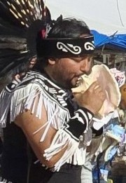 Pahrump Social Powwow - image of a male member of the Gourde dancers team blowing into a conch shell