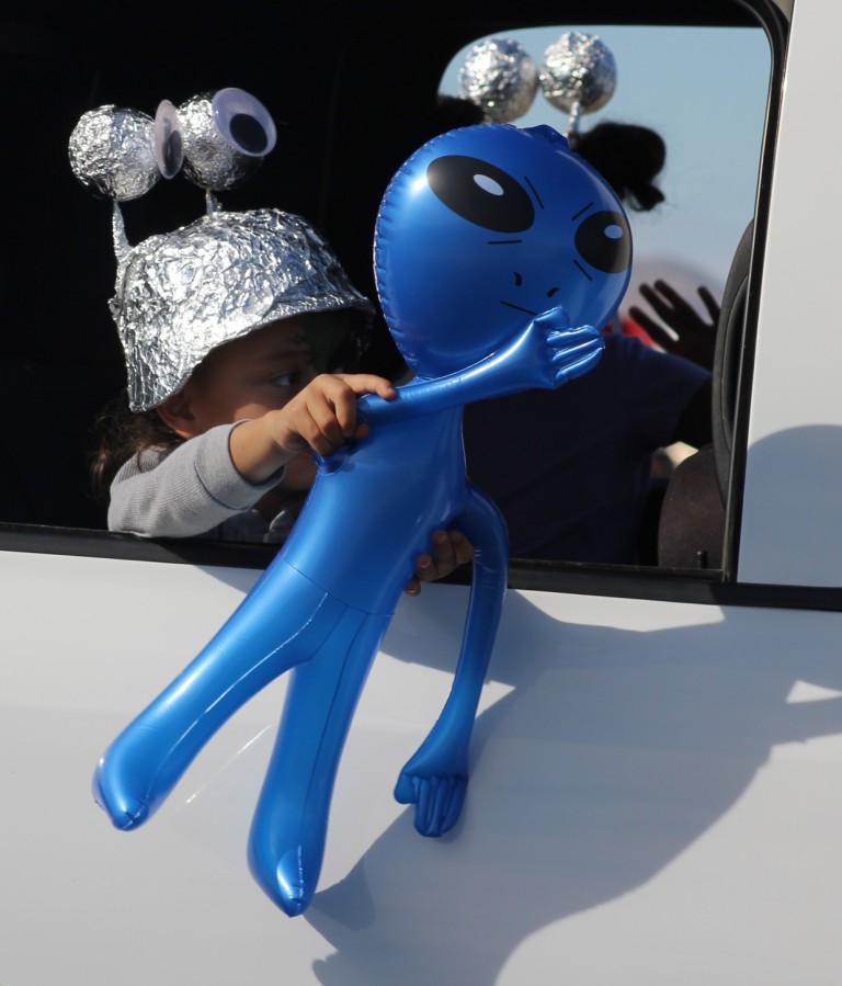 Pahrump Fall Festival Parade & Car Show - image of a small child wearing a tinfoil helmet holding an inflatable alien.