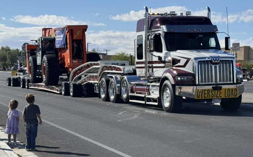 Pahrump Fall Festival Parade - a brother and sister, ages three and five, stand enthralled by the huge tractor-trailer carrying a crane.